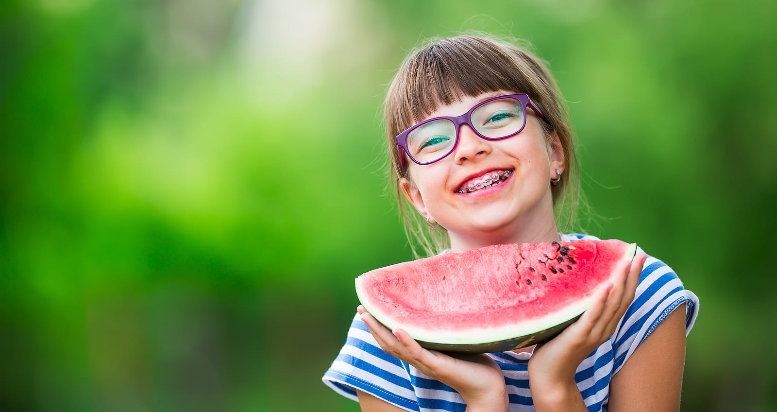 A child wearing braces and eating watermelon