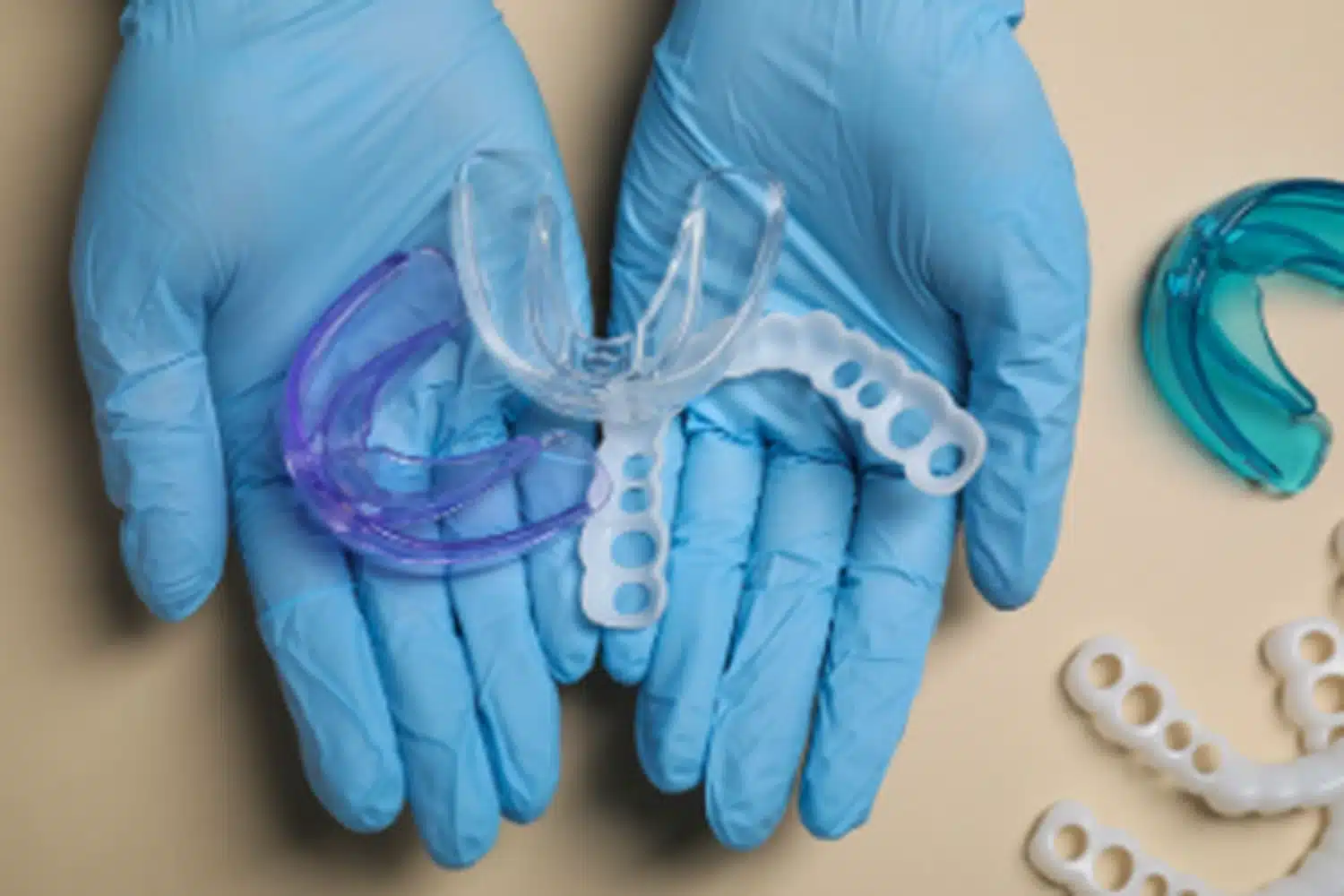 Dentist wearing medical gloves holding various mouth guards for teeth protection